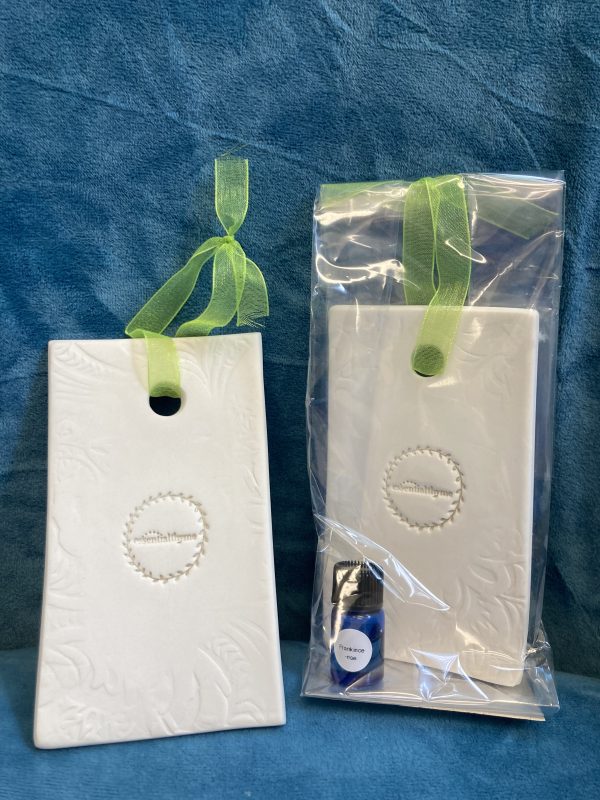 2 ceramic diffusers one showing mini essential oil bottle in packaging